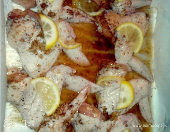 Я вначале противень с бортиками  застилаю фольгой, а потом пергаментной бумагой. Выкладываем курицу и выливаем маринад вместе со специями и чесноком (они  оседают на дно). Сверху на каждый кусочек кладем  лимон.