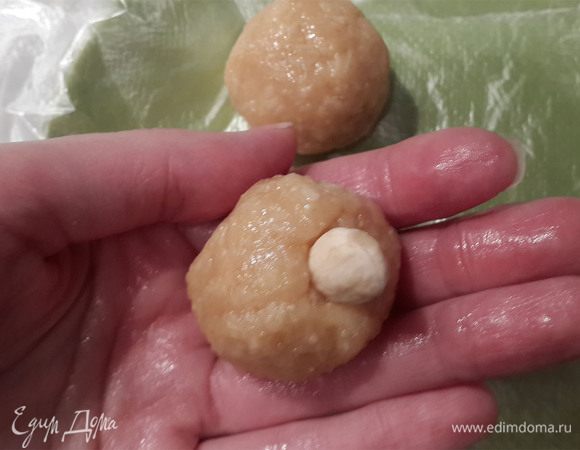 Когда масса остынет и станет еле теплой, она застынет и можно лепить шарики, величиной чуть больше грецкого ореха. В каждый положить миндаль. Выложить на тарелку, устланную пленкой и поставить в холодильник до полного застывания (от 20- 30 минут).
