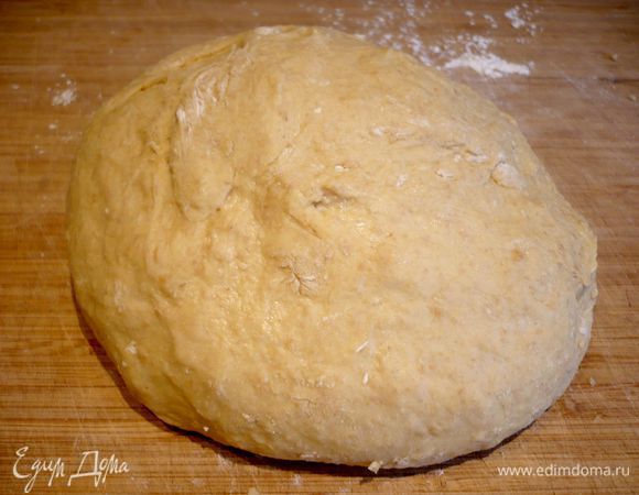 Теперь начнем постепенно по ложечке столовой добавлять муки и вымешивать тесто до эластичности. После добавления нескольких ложек тесто становится более однородным и меньше липнет к рукам. Выкладываем его на присыпанную мукой поверхность.