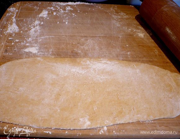 Присыпаем тесто сверху мукой, хорошо подпыляем доску и начинаем раскатывать тесто в удлиненный пласт, двигая скалку только вверх и вниз, пока толщина теста не достигнет максимум нескольких миллиметров.  