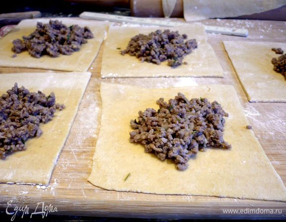 Ширина такого пласта должна примерно составить 12 см. Теперь разрезаем наше тесто примерно на 3 равных квадрата (со стороной 12см). Заполняем их начинкой (примерно 1 ст.л. на квадратик), скрепляем в треугольнички и кладем на присыпанную мукой поверхность. Накрываем полотенцем. То же самое проделываем с тремя остальными кусочками теста.  