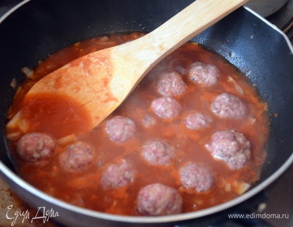 В сковороду к доведенным до прозрачного цвета луку и чесноку добавляем нарезанные томаты и сок, оставляем закипать. Когда соус начнет закипать, выкладываем фрикадельки, закрываем крышкой и готовим на среднем огне около 10 минут, периодически помешивая.
