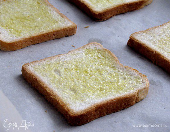 Смажьте хлеб при помощи кисточки оливковым маслом и положите на противень, застеленный пекарской бумагой. Поставьте противень под разогретый гриль (180 град) на 2-3 минуты, чтобы хлеб слегка зазолотился.