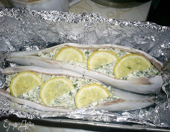 Полученной начинкой фаршируем рыбку, половинки кусочков лимона выкладываем сверху на начинку. Форму для запекания выстилаем фольгой и выкладываем рыбку брюшком вверх.