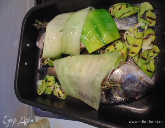 На рыбу положить веточку розмарина, рыбу завернуть в листы порея. Положить рыбу в смазанную оливковым маслом форму, рядом с рыбой выложить колечки порея, добавить вино, сбрызнуть оливковым маслом. Выпекать 25 минут при температуре 200 гр С. Если лук будет подгорать, прикрыть форму фольгой.
