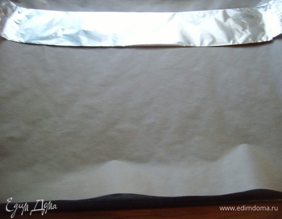 Подготовить противень: на пергаментную бумагу в середине противня поместить ленту из сложенной в несколько раз фольги. У фольги сделать бортик, чтобы тесто не выливалось за её края. Бортик смазать маслом. Другими словами поверхность теста должна быть по величине половины противня: 35х18 см. Пармезан натереть на тёрке.