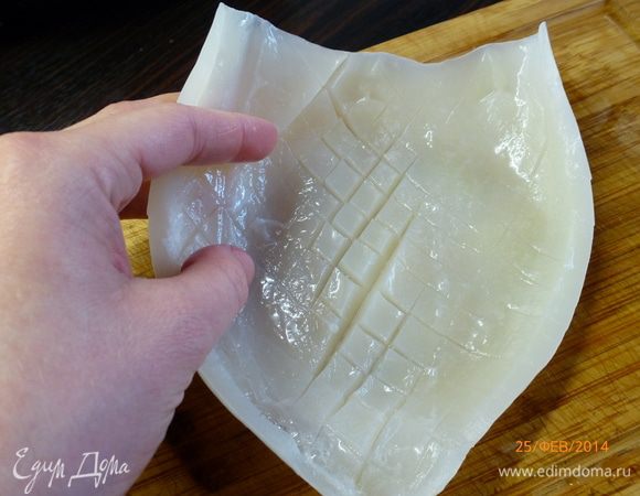 У меня 3 тушки кальмаров, это примерно 220 г. Очищенные тушки кальмара разрезаем вдоль.  Тушку кальмара кладем внутренней стороной вверх. Чтобы при жарке кальмар был мягче, делаем насечки. Слегка надрезаем поверхность кальмара как на фото (не насквозь!). Должна получиться сетка из ромбиков. 