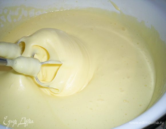 Теперь, не прекращая взбивания, сначала добавляем 2 столовые ложки кипятка, а затем тонкой струйкой вливаем масло и взбиваем до однородной густой пышной массы. При этом ее консистенция изменится, масса станет плотнее.