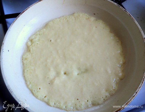 В сковороде разогреть растительное масло. Выложить по центру немного теста и быстро распределить его ложкой в тонкий пласт. 