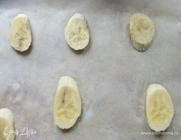Банан порезать дольками, выложить на противень, застеленный пекарской бумагой, на довольно большом расстоянии друг от друга.