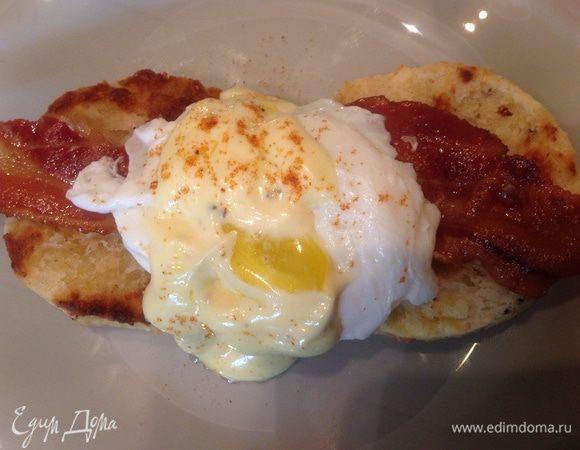 Собираем бутерброд: на две булочки кладем бекон, сверху яйцо пашот и поливаем соусом.