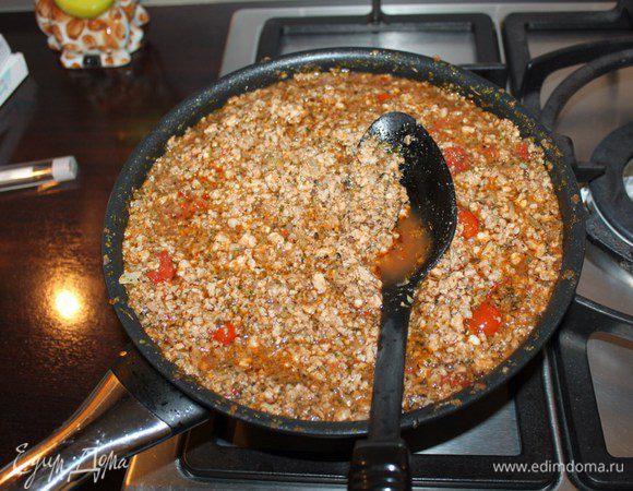 Налить в сковороду оливковое масло и разогреть в течение пяти минут. Порезать лук и 2 зубчика чеснока и протушить 1 минуту. Добавить фарш, банку резаных томатов, томатную пасту, соль, красное вино полстакана (я выбрала красное винтажное), полученный томатный соус   продолжить тушить, затем добавить 3 ст.л. ложки орегано и 1 ст. л. базилика и продолжать тушить в течение получаса на небольшом огне.