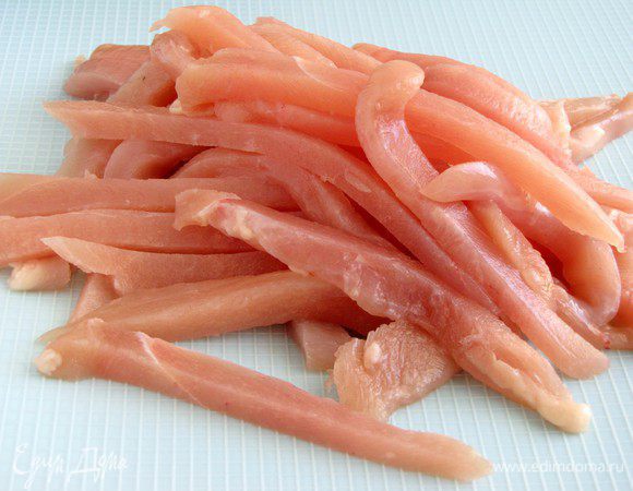 Куриное филе нарезать тонкими длинными полосками. Лучше это делать, когда мясо немного подморожено.