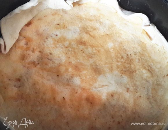 Вырезать из теста 2 круга. Один поменьше, другой- побольше. Меньшую заготовку переложить в разъемную форму, устланную пергаментом. Смазывать пергамент не нужно.  Должны получиться небольшие бортики (около 2-3 см высотой).  Поверх теста уложить один блинчик. И выкладывать слоями начинки. 