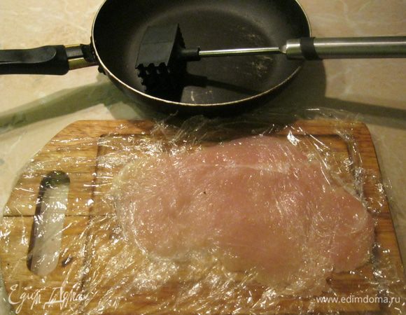 Половинки филе разрезал пополам, чтобы получилось четыре тонких куска. Разделочную доску обернул пищевой пленкой, выложил на него один кусок филе и накрыл его пленкой. Отбил сначала молоточком, а потом сковородкой. И так же поступил с остальными кусками. Получились большие, но тонкие куски филе.