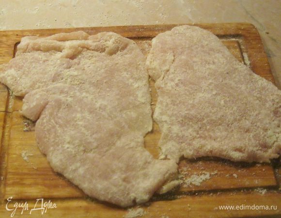 Для панировки смешал столовую ложку натертого в порошок пармезана (вы можете взять любой твердый сыр) и столько же пшеничной муки, а еще добавил немного молотого черного перца.
Куски отбитого филе хорошенько запанировал и разложил на доске. Еще не готово, но уже аппетитно выглядит.
