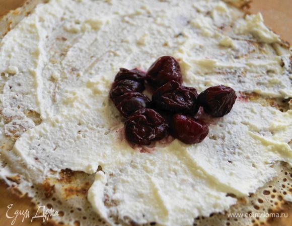 Блин смазать небольшим слоем творожной массы и положить несколько вишен.