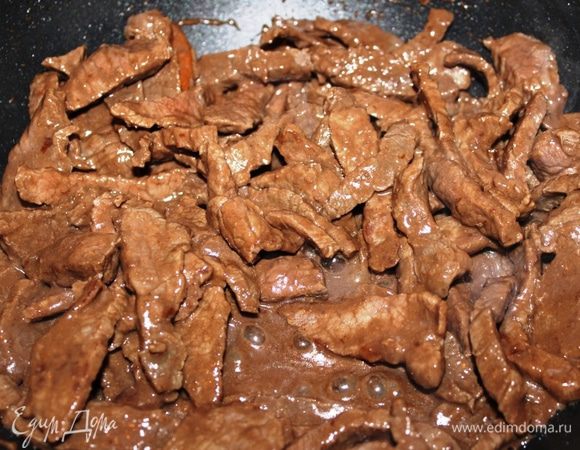 Телятину хорошо промыть и нарезать на длинные полоски поперек волокон мяса (это важно, т.к. мясо получается очень мягким). Для начала необходимо мясо обсушить и поджарить при сильном огне на той же сковороде, где пассеровали лук и морковь. Кусочки должны обжариться только сверху, поэтому необходимо жарить его небольшими порциями. Каждую порцию после обжарки складывать в отдельную миску.