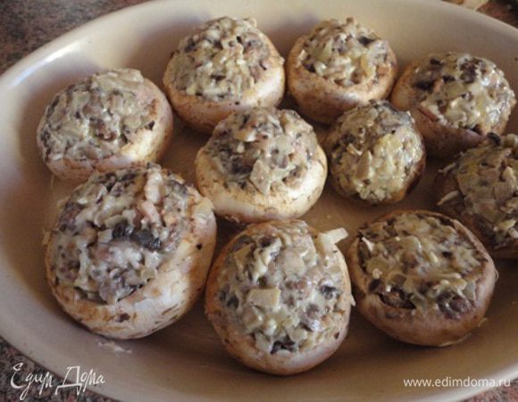 Грибы наполнить начинкой. У меня получается с горкой. Выложить их в форму, смазанную сливочным маслом, посыпать сыром. Запекать в духовке при температуре 200 градусов 15 минут.