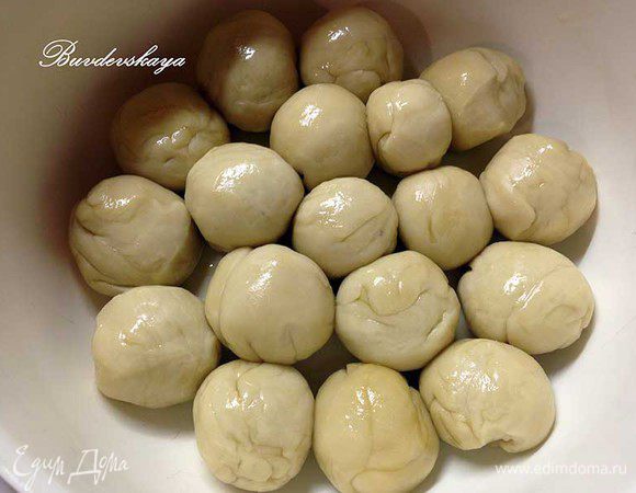 Затем тесто тщательно размять и разделить на равные кусочки, скатав из них  шарики размером с маленький мандарин (у меня получилось 18 штук). Смазать шарики оставшимся  оливковым маслом, завернуть в пищевую  пленку и оставить еще минимум на 30 минут. 