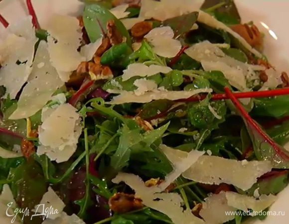 Салатные листья полить заправкой, перемешать и выложить на блюдо, сверху разложить орехи и хлопья сыра.