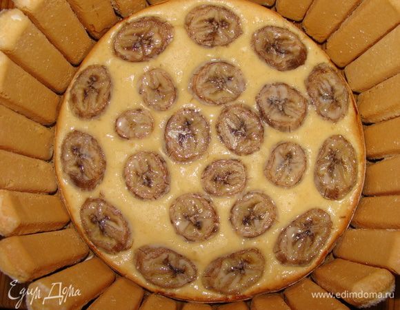 Готовый корж я поместила в разъемную форму большего диаметра (26см). Смазала ее сливочно-ванильным ликером. По бокам установила печенье.