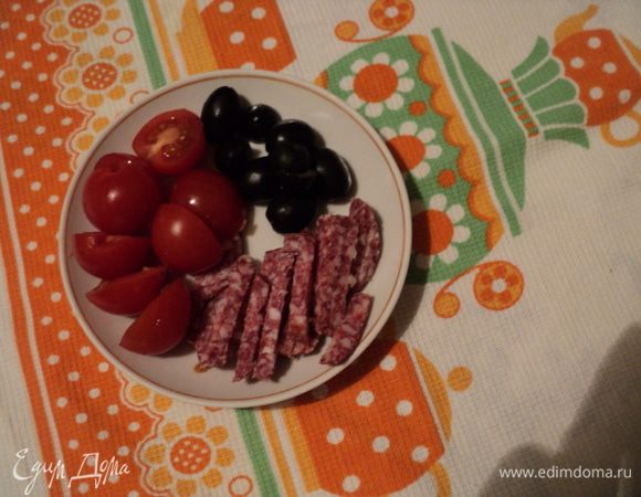Колбасу нарезать тонкими ломтиками, затем кусочками, помидорчики черри, нарезать напополам, нарезать оливки.