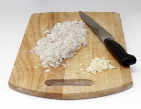 Начнем с чеснока и лука. Раздавим дольки чеснока, удалим серединку - «зло» и мелко нарежем. Мелко шинкуем лук. 