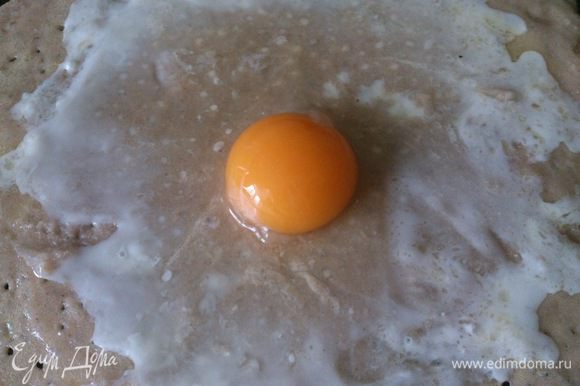На середину блинчика вылить яйцо и слегка растянуть белок по поверхности.