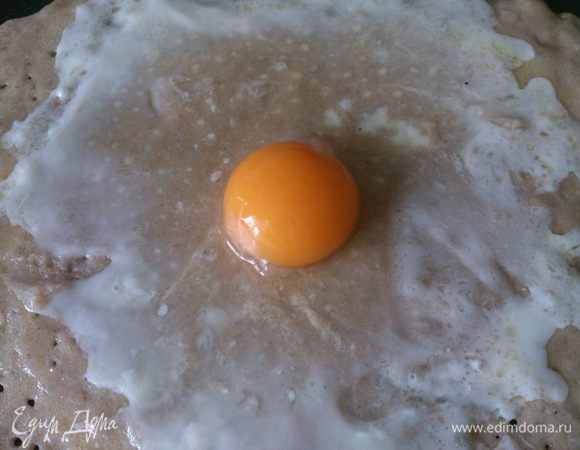 На середину блинчика вылить яйцо и слегка растянуть белок по поверхности.