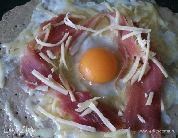 Вокруг желтка разложить сыр, сверху ветчину и сверху еще немного сыра.