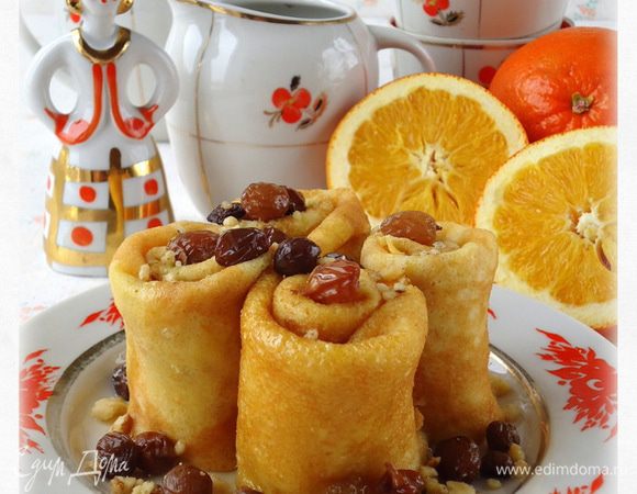 Блинчики скрутить в рулоны, поставив на тарелку полить их сиропом с орехами и изюмом.
