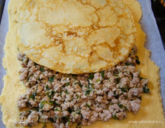 Выложить на тесто мясную начинку, оставляя поля. Проложить блинами.