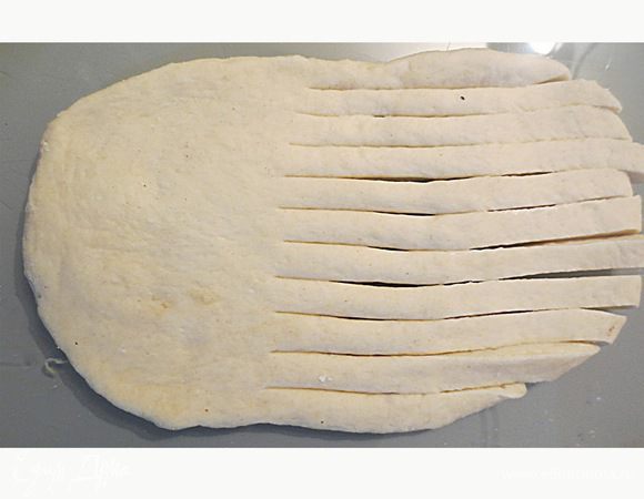 Начинаем работу с тестом.
Сделала 2 вида пирожков один из которых по форме, напоминает рогалик, а вторая форма в виде цветка.
Начнем в 1-й формы.
Раскатываем тесто в виде колбаски, и разрезаем на кусочки. Из каждого кусочка раскатываем овал, один конец которого разрезаем на полоски 0,8 мм шириной. Разрезаем примерно до середины формы. 