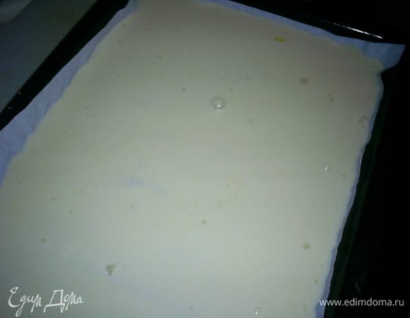 Теперь постепенно вливаем оставшееся молоко и размешиваем тесто до однородности. Добавляем взбитые вилкой яйца, перемешиваем. Последним добавляем растопленное сливочное масло и тщательно размешиваем. Тесто получается довольно жидким. Оставляем его на 10-15 минут отдохнуть, а сами включаем духовку. На 180 градусов с конвекцией или 200 градусов без нее.
Тесто выливаем на противень, застеленный бумагой для выпечки. Края бумаги должны выходить за бортики.
В оригинале рецепта рекомендовалось выпекать наш блин на противне 35*45см. У меня такого нет. Я выпекала на двух противнях - 35*25см и 30*20см.