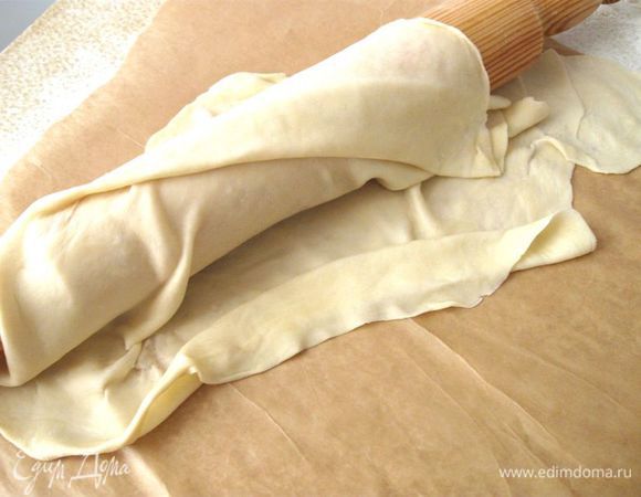 Снова тянуть руками. Это лучше делать на  бумаге для выпечки. Удобно положить тесто на кулак и потихоньку растягивать. Тесто должно стать почти прозрачным, но не порваться. Так же поступить с другим куском. 

