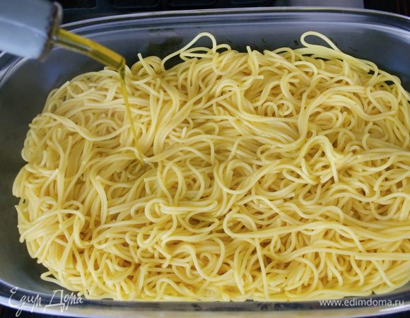 Готовые спагетти слить, переложить в большое прямоугольное блюдо с бортиками и полить оливковым маслом, чтобы они не слиплись. 