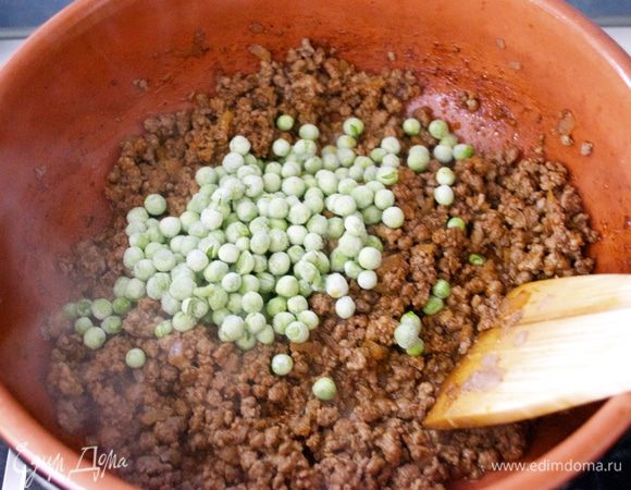 К почти готовому фаршу добавить замороженный горошек. Как только начинка будет готова, переложить ее в блюдо, дать остыть, закрыть пищевой пленкой и убрать в холодильник.