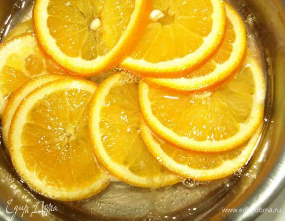 Сахар растворяем в воде, доводим до кипения. Добавляем нарезанные тонкими кружками апельсины и варим 20 минут, пока кожура не станет мягкой.