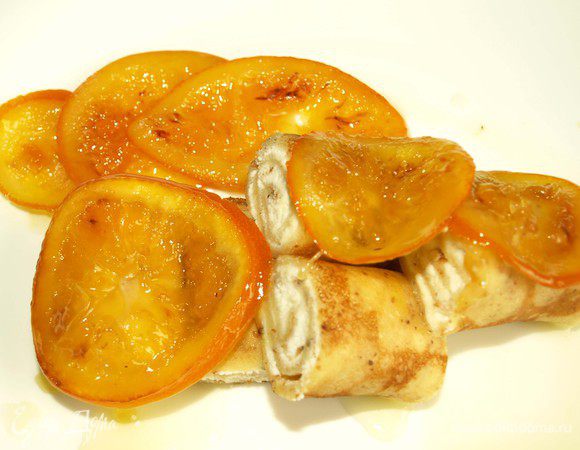 Достать из холодильника блины, нарезать их кусочками, выложить на тарелку. Полить апельсиновым сиропом и сверху выложить карамелизированные апельсины.