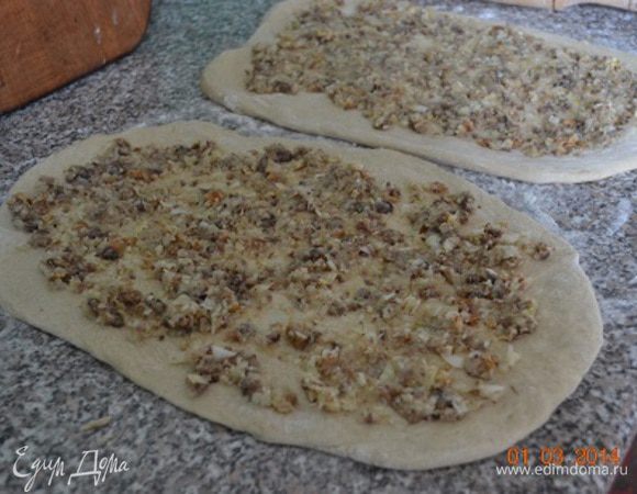 Подошедшее тесто делим на 2 части, каждую раскатываем в тонкий пласт, равномерно наносим начинку.