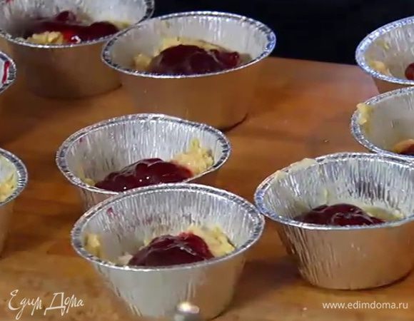 Формы для маффинов смазать оставшимся сливочным маслом, разложить в них тесто на половину объема, в каждую форму положить по 1 ч. ложке малинового джема.