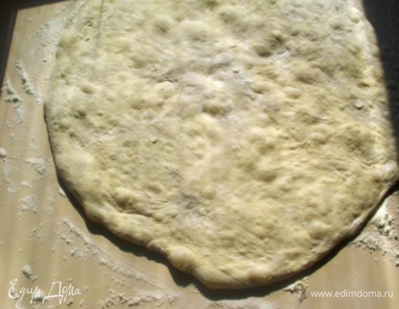 Тем временем  рабочую поверхность щедро присыпать мукой  (автор использует цельнозерновую) и аккуратно переместить на неё тесто. Просто дайте ему сползти, слегка помогая рукой. Тесто сверху также присыпать и легко нажимая ладонью, сформировать лепешку, 
