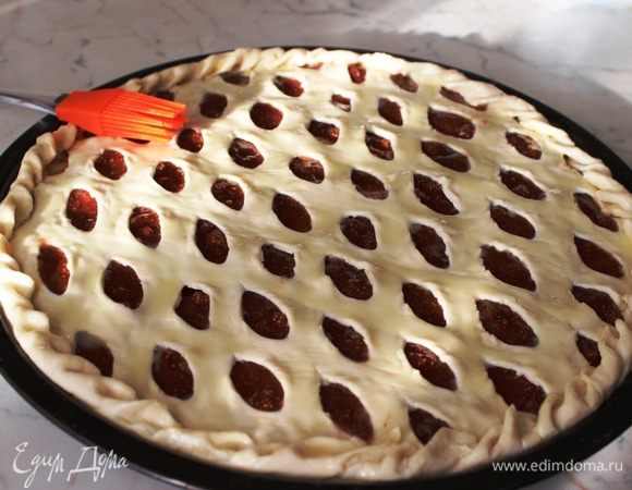 Лишние концы теста обрезать с помощью ножниц, завернуть края пирога и смазать тесто растопленным маслом.