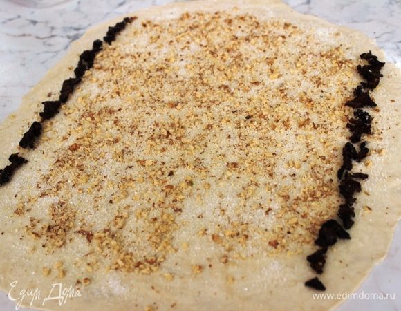 Тесто раскатать, смазать растопленным маслом, присыпать сахаром и измельченными орехами. По краям выложить нарезанный изюм - параллельными полосками (можно обойтись и без изюма, кто не очень его любит)