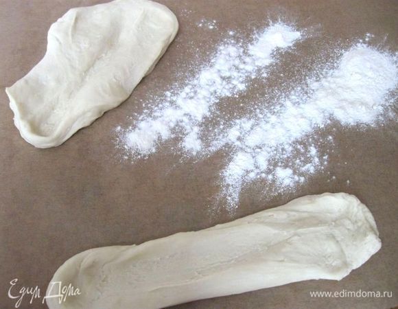 Разделить тесто на  2 куска. Сделать из каждого лепешку. Аккуратно растягивать каждую  во все стороны на рабочей поверхности, чуть присыпанной мукой, потом накрыть влажной тканевой салфеткой и дать постоять несколько минут. 
