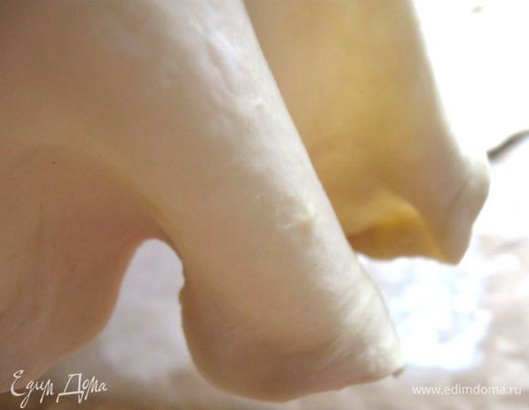  Затем снова  аккуратно тянуть  руками пласты теста, раскатать  скалкой. Делать это на  бумаге для выпечки. Посыпьте кисти рук мукой, разотрите ее, положите тесто на тыльную сторону кулака, и тяните, сначала от середины, потом ближе к краям. 