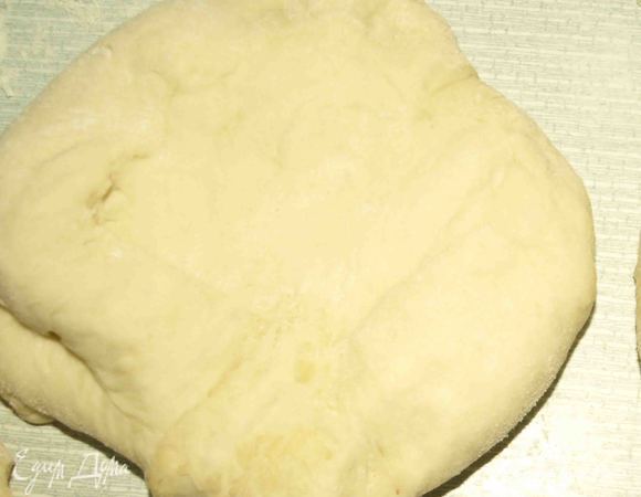 Когда тесто увеличится, то его хорошо выбиваем и разделяем на две части. Одну часть отправляем назад в миску. Второю делим на 4 части. Раскатываем на припыленной мукой  доске лепешки диаметром 15-18 см. Отправляем на противень, накрываем промасленной бумагой и оставляем в теплом месте на 15 минут. 