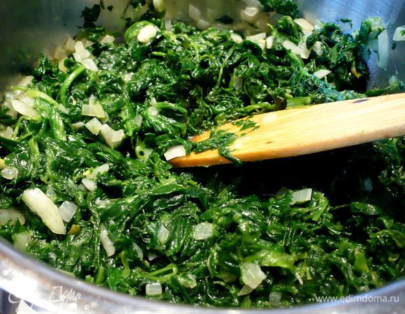 Тем временем лук чистим и режем мелко, чеснок натираем на терке, шпинат слегка размораживаем. В сотейнике разогреваем немного оливкового масла. Обжариваем на нем лук и чеснок, добавляем шпинат и тушим его до готовности. Добавляем соль, перец, немного лимонного сока и мускатный орех. Перемешиваем. Помидоры режем кольцами. 50 г орехов рубим, а пармезан натираем на мелкой терке. 