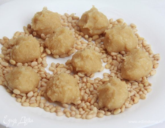 Тесто вынуть из холодильника, разделить на 10 частей, каждую скатать в шар.  Миндальные шарики выложить на орешки, слегка придавить.